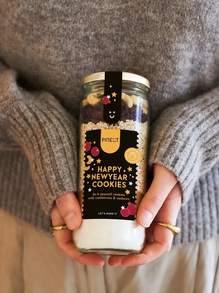 Handen houden een Happy Newyear cookie-pot vast als eindejaarsgeschenk voor relaties